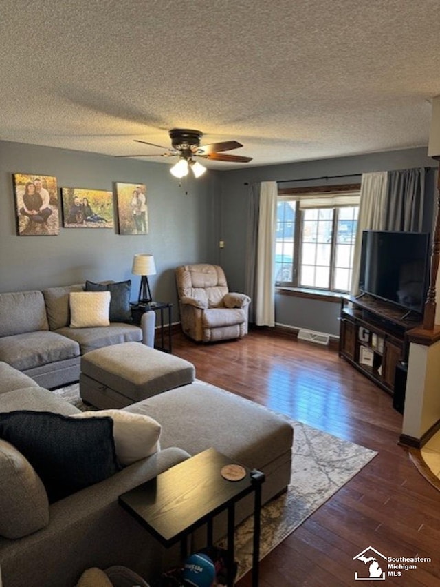 living room featuring visible vents, dark wood-type flooring, a ceiling fan, a textured ceiling, and baseboards