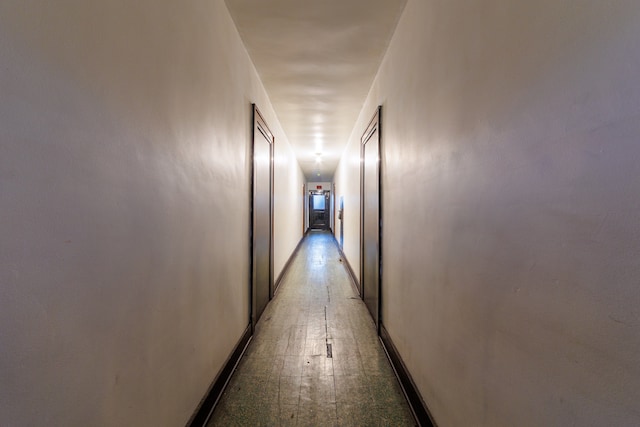 hall featuring baseboards and light floors