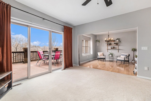 sitting room featuring carpet floors, visible vents, baseboards, and ceiling fan with notable chandelier