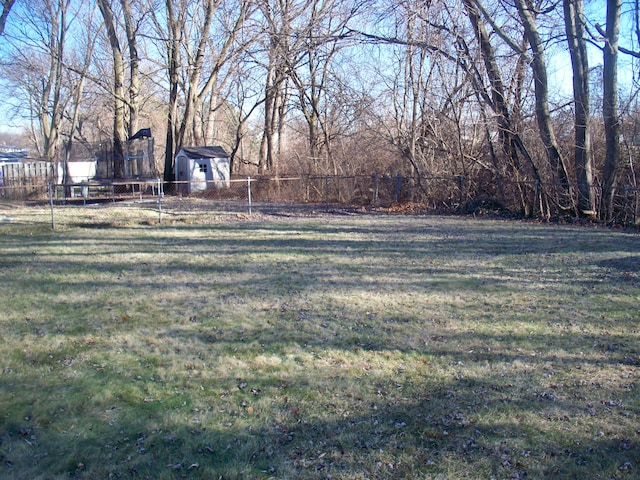 view of yard with a fenced backyard, a storage unit, and an outbuilding