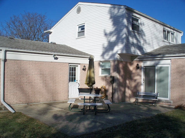 rear view of house featuring brick siding and a patio area