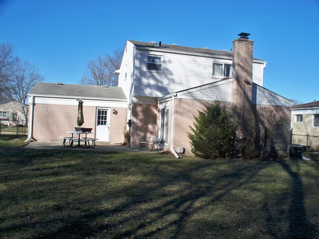 back of property featuring a patio, central AC unit, brick siding, a lawn, and a chimney