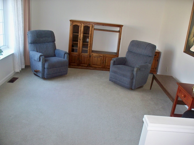 sitting room with visible vents and light colored carpet