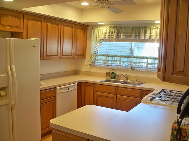 kitchen featuring light countertops, white appliances, brown cabinets, and a sink