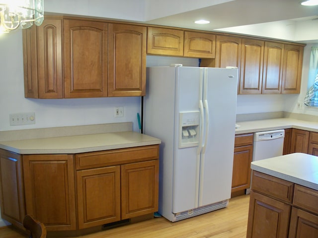 kitchen featuring brown cabinetry, white appliances, light countertops, and light wood-style flooring