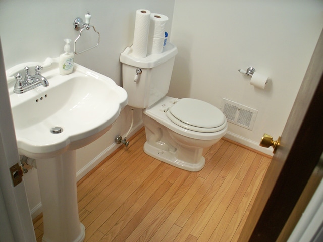 bathroom with toilet, baseboards, visible vents, and wood finished floors