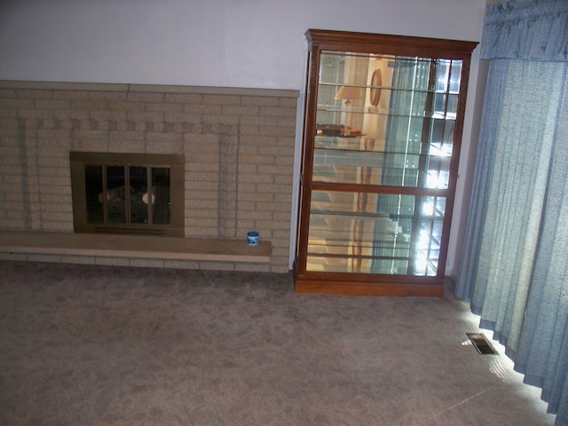 unfurnished living room with carpet flooring, a fireplace, and visible vents