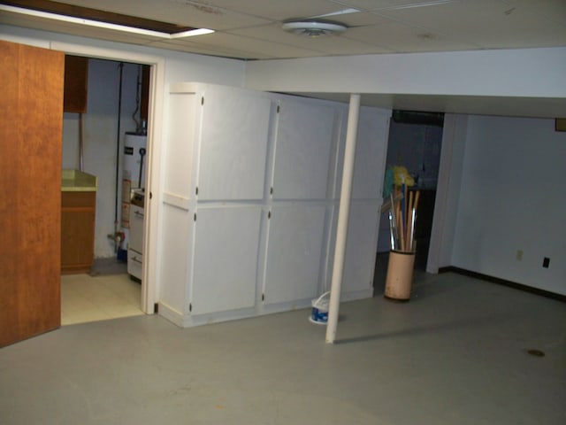 finished below grade area featuring gas water heater, a drop ceiling, and baseboards