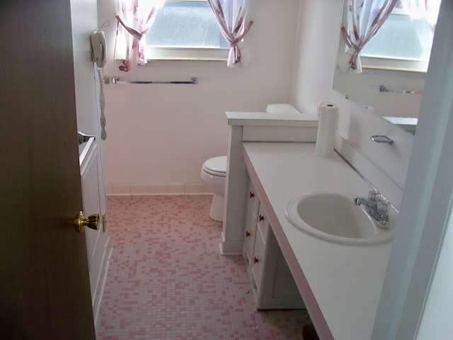 bathroom featuring toilet, tile patterned floors, baseboards, and vanity