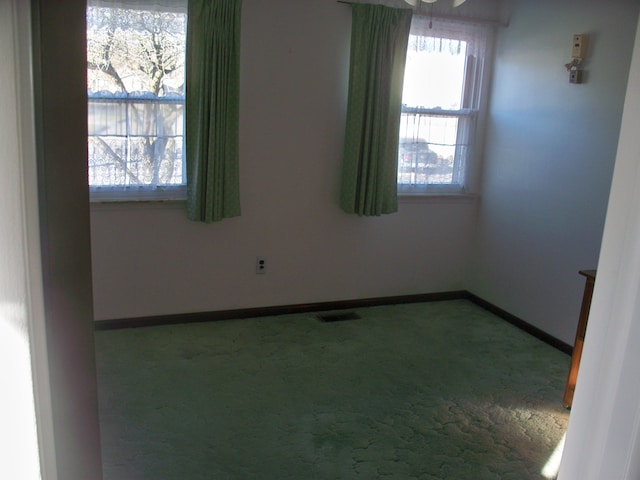 empty room with carpet flooring, visible vents, and baseboards