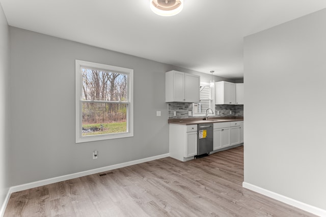 kitchen with tasteful backsplash, white cabinetry, light wood-style floors, and baseboards