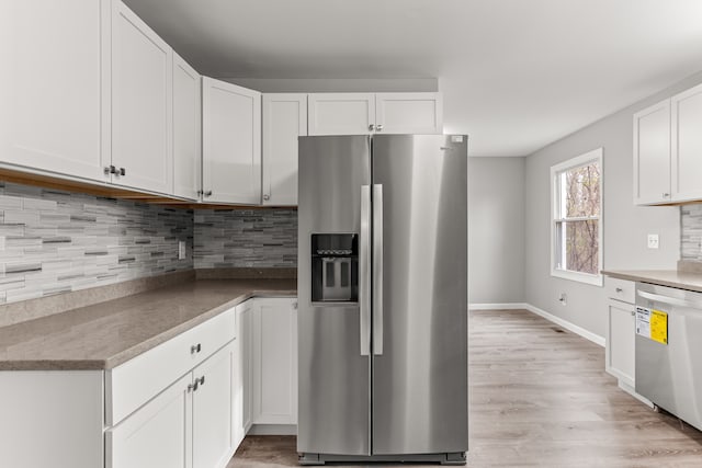 kitchen with baseboards, white cabinets, appliances with stainless steel finishes, decorative backsplash, and light wood finished floors