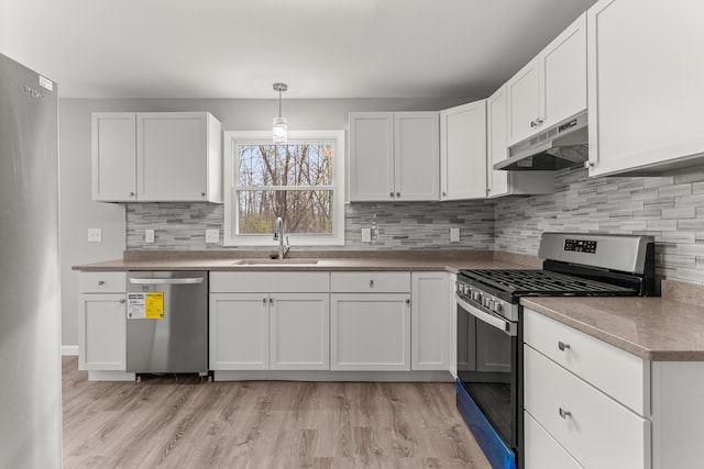 kitchen with light wood-style flooring, under cabinet range hood, a sink, white cabinets, and appliances with stainless steel finishes