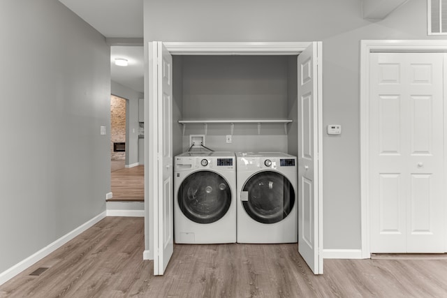 laundry area featuring washing machine and dryer, laundry area, baseboards, and wood finished floors