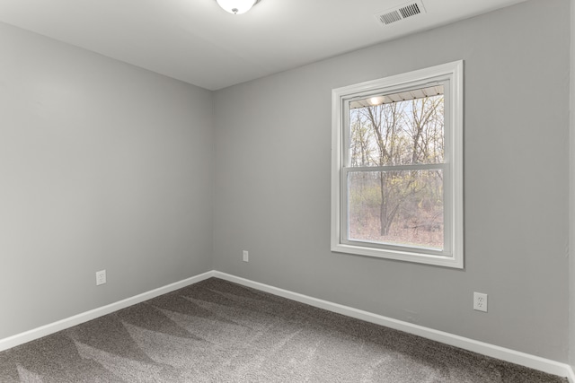 empty room featuring dark carpet, visible vents, and baseboards