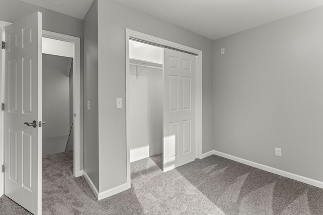 unfurnished bedroom with a closet, carpet flooring, and baseboards