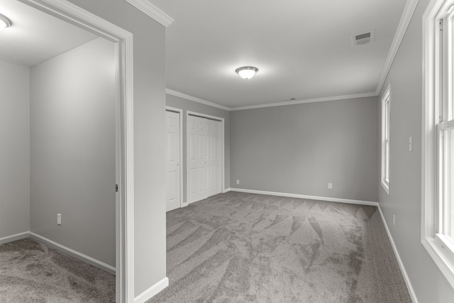 unfurnished bedroom featuring carpet floors, visible vents, ornamental molding, and baseboards