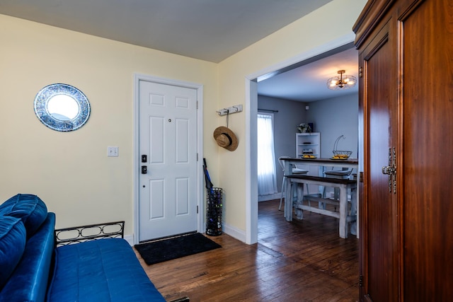 entryway with a notable chandelier, dark wood-style flooring, and baseboards