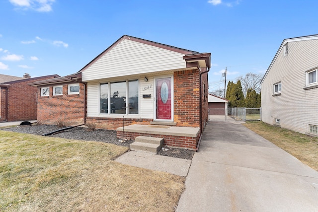 view of front facade featuring a front yard, brick siding, and a detached garage