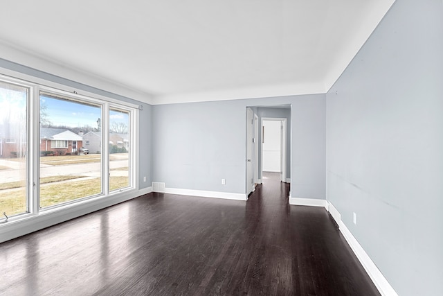 spare room featuring visible vents, dark wood finished floors, and baseboards