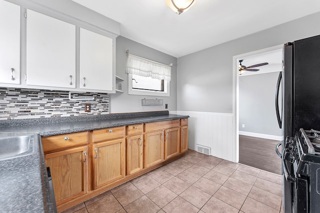 kitchen featuring black range with gas cooktop, light tile patterned flooring, a wainscoted wall, visible vents, and a ceiling fan