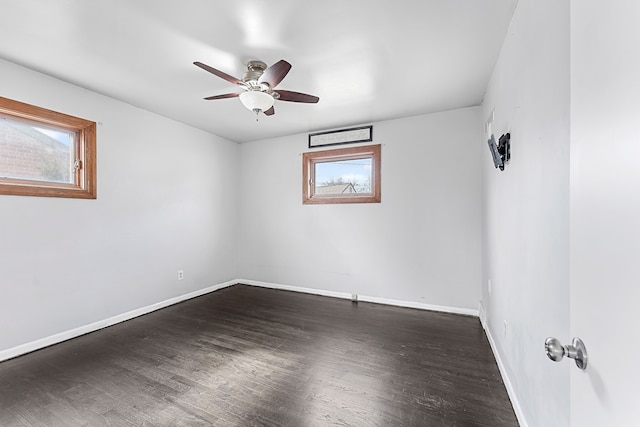 empty room with ceiling fan, dark wood-type flooring, plenty of natural light, and baseboards