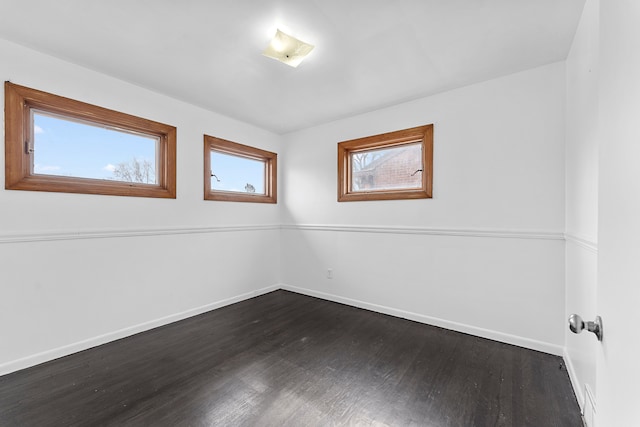 unfurnished room with dark wood-style flooring and baseboards