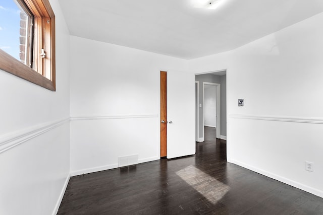 empty room with baseboards, visible vents, and wood finished floors