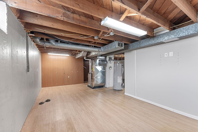 unfinished basement featuring water heater, wood walls, wood finished floors, and heating unit