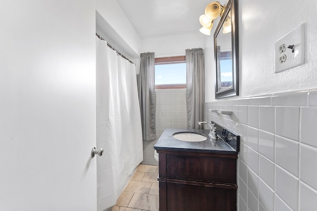 bathroom with a wainscoted wall, tile walls, a shower with shower curtain, vanity, and tile patterned floors