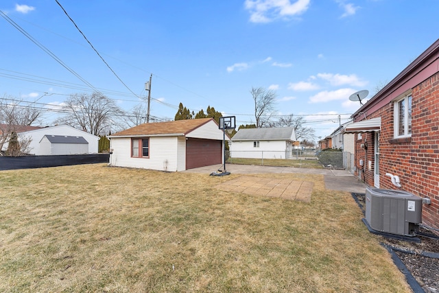 view of yard featuring a garage, cooling unit, fence, and an outdoor structure