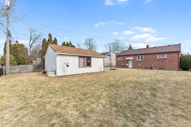 rear view of house featuring fence, a lawn, and brick siding