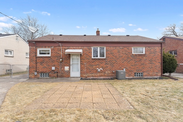 back of house featuring a yard, brick siding, fence, and a gate