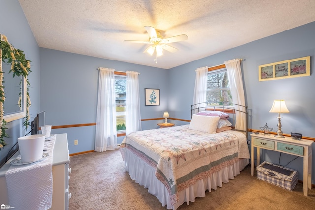 bedroom with ceiling fan, baseboards, a textured ceiling, and light colored carpet