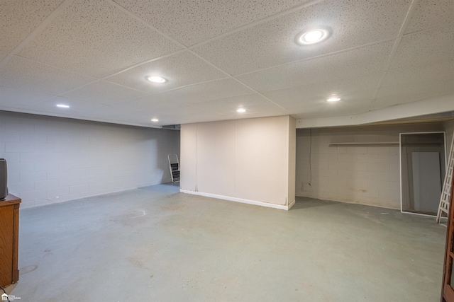 finished basement with concrete block wall and recessed lighting