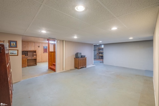 finished below grade area featuring concrete block wall, a paneled ceiling, and recessed lighting