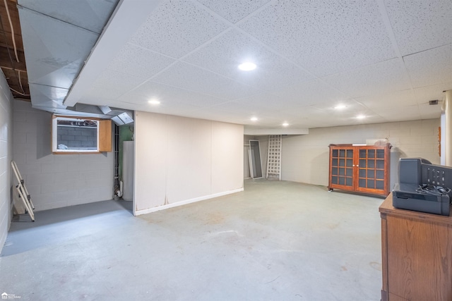 finished below grade area featuring concrete block wall, a drop ceiling, and recessed lighting