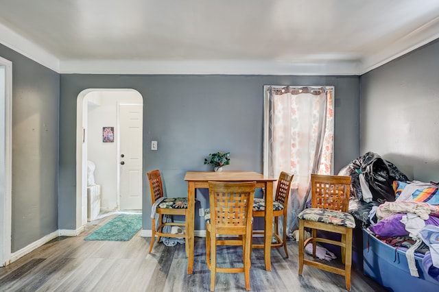 dining space with wood finished floors, arched walkways, and baseboards