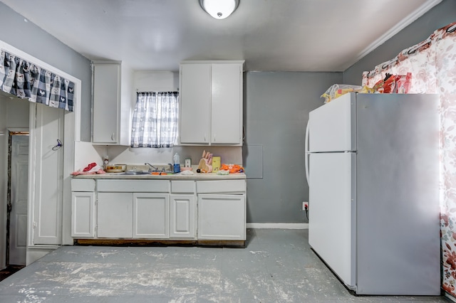 kitchen with light countertops, white cabinets, concrete floors, and freestanding refrigerator