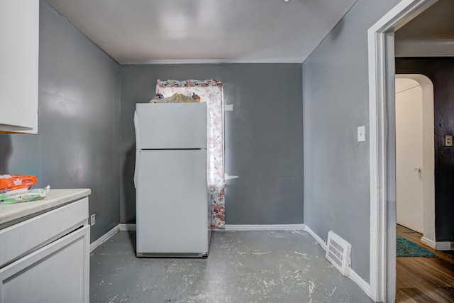 kitchen with visible vents, baseboards, white cabinets, and freestanding refrigerator