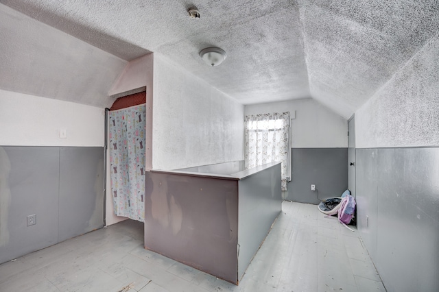 bonus room with a textured ceiling and vaulted ceiling