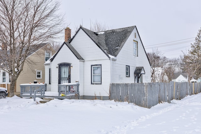 view of front of property with a chimney, roof with shingles, and fence