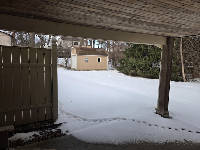 yard layered in snow with a storage unit and an outdoor structure