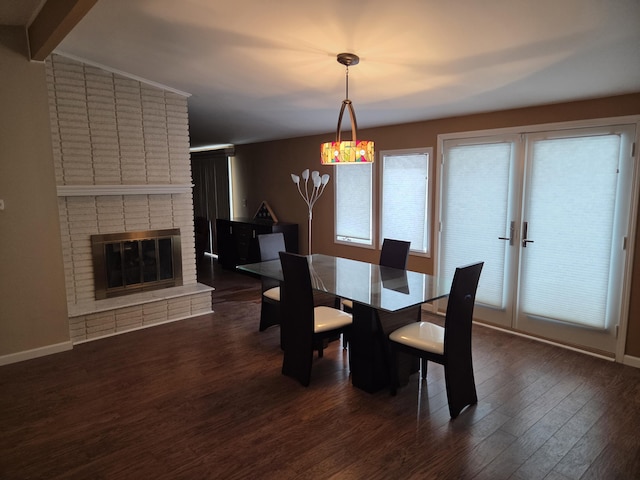 dining room with dark wood-type flooring, a fireplace, and baseboards