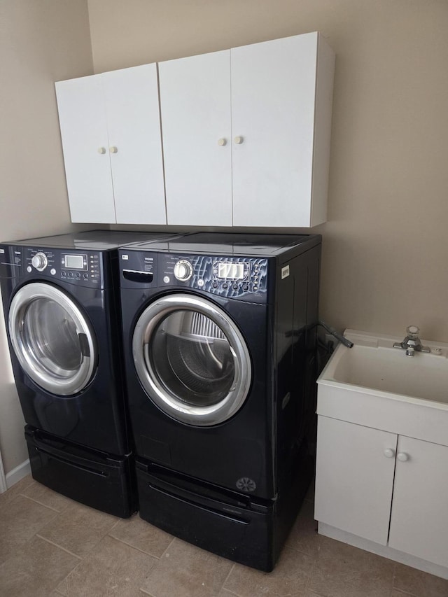 clothes washing area featuring separate washer and dryer, a sink, and cabinet space