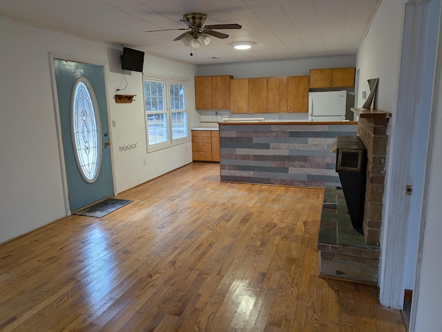 kitchen featuring ceiling fan, light wood-style flooring, brown cabinets, freestanding refrigerator, and light countertops