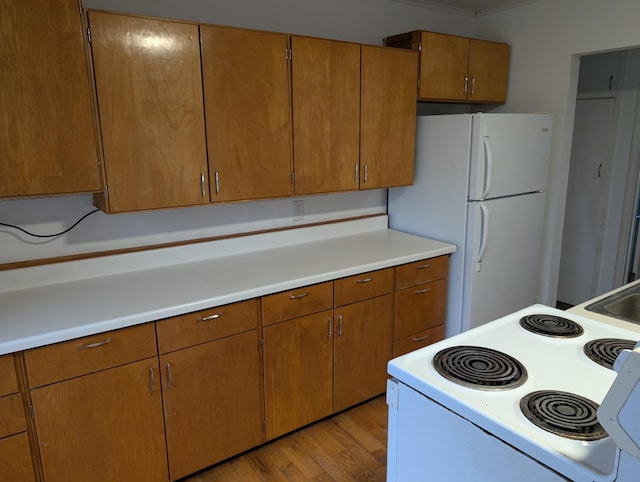 kitchen featuring white appliances, light countertops, light wood finished floors, and brown cabinetry