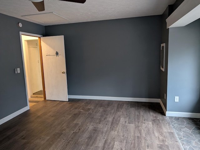 unfurnished room with ceiling fan, dark wood-style flooring, attic access, and baseboards