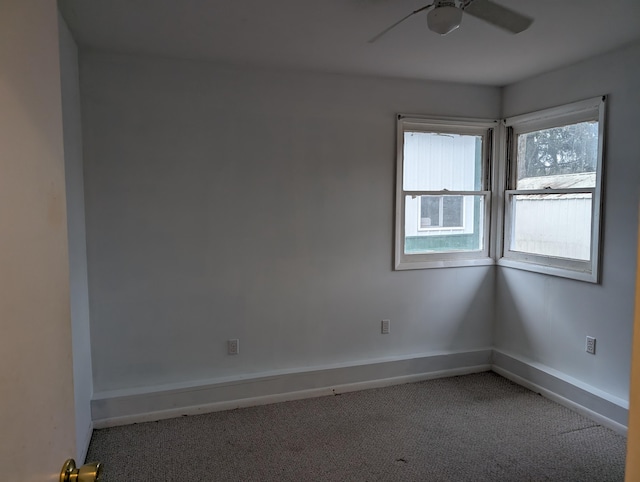 carpeted spare room with a ceiling fan and baseboards