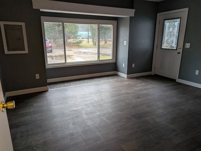 unfurnished room with electric panel, dark wood finished floors, and baseboards